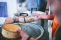 The hands of the poor handed a plate to receive food from volunteers to alleviate hunger, the concept of helping the homeless