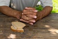 Hands the poor old man`s, piece of bread and change, pennies on wood background. The concept of hunger or poverty. Royalty Free Stock Photo