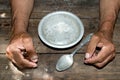 hands the poor old man& x27;s and empty bowl on wood background. The Royalty Free Stock Photo