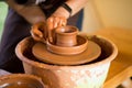 Hands of potter makes pottery dishes on potter wheel. Sculptor in workshop makes clay product Royalty Free Stock Photo