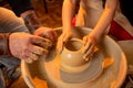 The hands of the potter and the hands of the child work with clay on a special machine Royalty Free Stock Photo