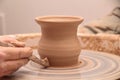 Hands of a potter, creating an earthen jar on pottery wheel.