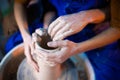 Hands of potter and his female student. Man and woman working together, creating clay product on potter wheel Royalty Free Stock Photo