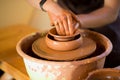 Hands of potter makes pottery dishes on potter wheel. Sculptor in workshop makes clay product Royalty Free Stock Photo