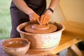 Hands of potter makes pottery dishes on potter wheel. Sculptor in workshop makes clay product Royalty Free Stock Photo