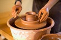 Hands of potter makes pottery dishes on potter wheel. Sculptor in workshop makes clay product Royalty Free Stock Photo