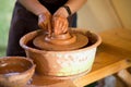 Hands of potter makes pottery dishes on potter wheel. Sculptor in workshop makes clay product Royalty Free Stock Photo