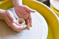 The hands of a potter sculpting a piece of clay on a rotating potter's wheel