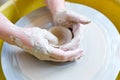 The hands of a potter sculpting a piece of clay on a rotating potter\'s wheel