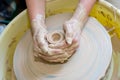 The hands of a potter sculpting a piece of clay on a rotating potter\'s wheel