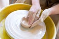 The hands of a potter sculpting a piece of clay on a rotating potter\'s wheel