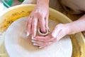 The hands of a potter sculpting a piece of clay on a rotating potter's wheel