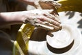 The hands of a potter sculpting a piece of clay on a rotating potter's wheel