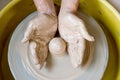 The hands of a potter sculpting a piece of clay on a rotating potter\'s wheel