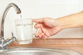 Hands pour fresh water into the glass under the tap in kitchen Royalty Free Stock Photo