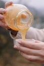 Hands pour honey from a jar into a saucer in autumn in Altai