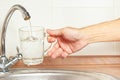 Hands pour water into the glass under the tap in kitchen Royalty Free Stock Photo