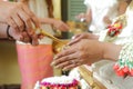 Hands pouring blessing water into bride's hands of Thai wedding.