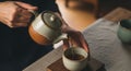 Hands pouring hot tea from a ceramic teapot into a cup Royalty Free Stock Photo