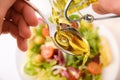 Hands pouring oil onto a spoon to dress salad top Royalty Free Stock Photo