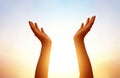 hands praying on blurred sunset sky background