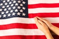 Hands of praying little girl on the background of the American flag. The concept of patriotism Royalty Free Stock Photo