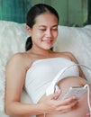 Hands of pregnant woman holding headset putting headphones to belly, motherhood concept