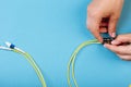 Hands prepare to tune a variable optic attenuator with a screwdriver. Blue background