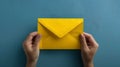 A Pair of Hands Holding a Bright Yellow Envelope Against a Blue Background. Simple and Clean Design. Perfect for Royalty Free Stock Photo