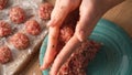 Hands press and shape a seasoned ground meat mixture.