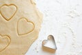 Hands pressing heart shaped cookie cutter into dough