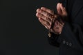 Hands of priest holding rosary and praying