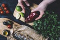 Hands in the process of cooking fish, pepper, parsley, tomato, lime on a cutting board on a black wooden background top view horiz