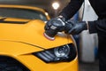 Hands of professional car service worker, with orbital polisher, polishing yellow luxury car hood Royalty Free Stock Photo