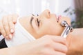 Hands of professional cosmetologist using facial roller massage instrument applying to the woman face in a beauty clinic Royalty Free Stock Photo