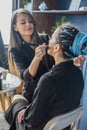 Hands of professional makeup artist applying eyeshadow concealer on eyes of female model use brush Royalty Free Stock Photo