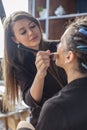 Hands of professional makeup artist applying eyeshadow concealer on eyes of female model use brush Royalty Free Stock Photo