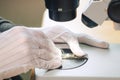 Hands of professional tech repairing small computer components on microscope table. Closeup. Electronics repair and fix