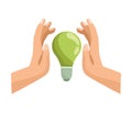 hands protecting green bulb
