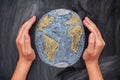 Hands protecting Planet Earth on black chalkboard background Royalty Free Stock Photo