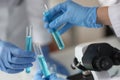 Hands in protective rubber gloves holding in test tube with blue liquid in laboratory Royalty Free Stock Photo