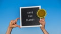 Hands of protester with text SAVE THE PLANET on black board on background of sunflower field. Reuse reduce recycle Royalty Free Stock Photo