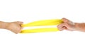 The hands pull yellow athletic elastic band in different directions. Close up. Isolated on white background