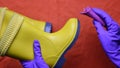 Hands in purple rubber gloves clean kids yellow rubber boots