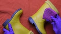 Hands in purple rubber gloves clean kids yellow rubber boots