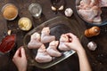 Hands put chicken wings in the baking dish.