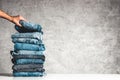 Hands, put the stack of blue jeans on gray background. Royalty Free Stock Photo