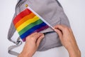 Hands putting an LGBT gay pride rainbow flag in a pocket of a backpack, pride parade preparations concept Royalty Free Stock Photo