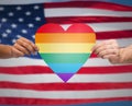 Hands with rainbow heart shape over american flag Royalty Free Stock Photo