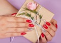 Hands with red artificial french manicured nails holding a gift box Royalty Free Stock Photo